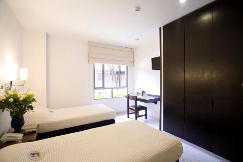 a bedroom with two beds and a desk and a window at Hotel Casa Santa Monica Norte in Cali