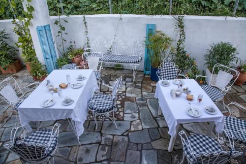 two tables and chairs with dishes on them on a patio at Pension Panos in Agios Dimitrios