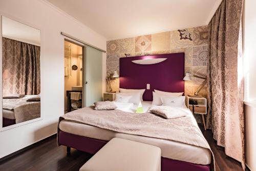 a bedroom with a large bed with a purple headboard at Retro Design Hotel in Langeoog