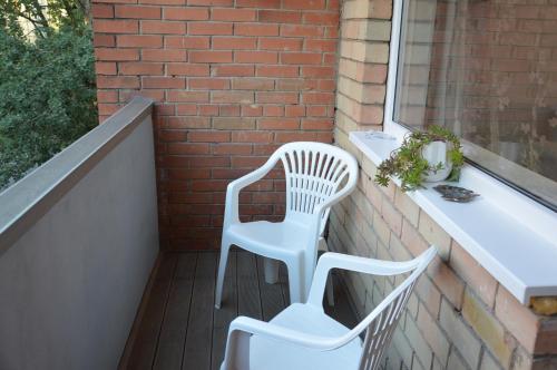 two white chairs on a balcony with a window at Alanta in Druskininkai