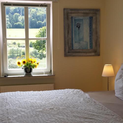 a bedroom with a bed and a window with a vase of flowers at ferienhaus-raju-zeltingen in Zeltingen-Rachtig