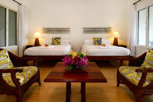 a hotel room with two beds and a table with flowers at Montpelier Plantation & Beach in Nevis