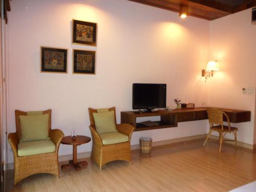 a living room with a tv and two chairs and a desk at VC@Suanpaak Boutique Hotel & Service Apartment in Chiang Mai