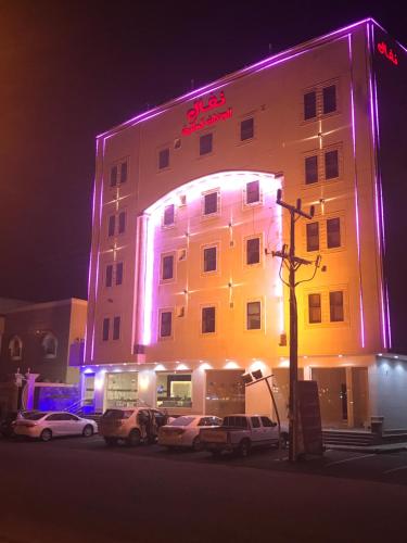 un edificio iluminado con coches estacionados frente a él en Nafal Hotel Suites, en Qal'at Bishah