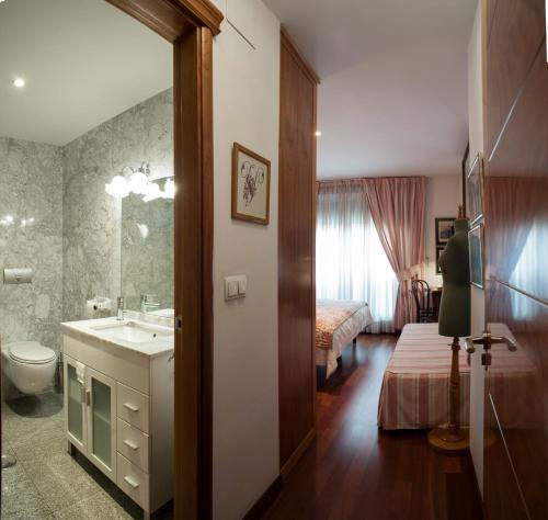 a bathroom with a sink and a toilet and a bed at Ch Hostal Victoria in Cuenca