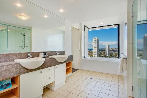 a bathroom with two sinks and a large window at Mantra Broadbeach on the Park in Gold Coast