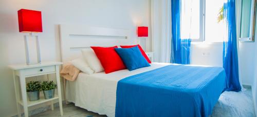 a bedroom with a bed with blue and red pillows at Manilva Beach 140 in Manilva