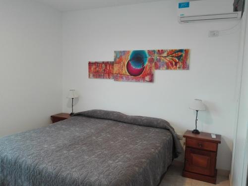 a bedroom with a bed and a painting on the wall at Tu Hogar en Neuquen in Neuquén
