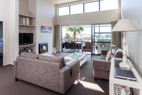 a living room with two couches and a large window at Sovereign Pier On The Waterways in Whitianga