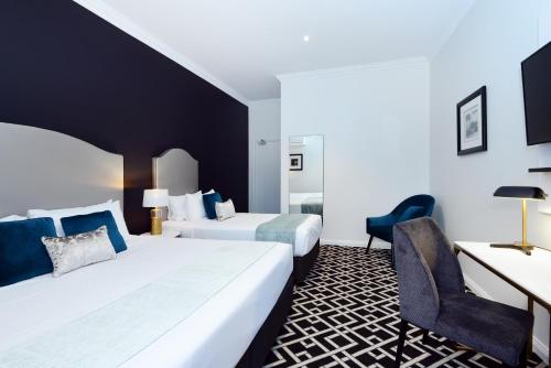 シドニーにあるHigh Cross Randwick by Sydney Lodgesのベッド2台とデスクが備わるホテルルームです。