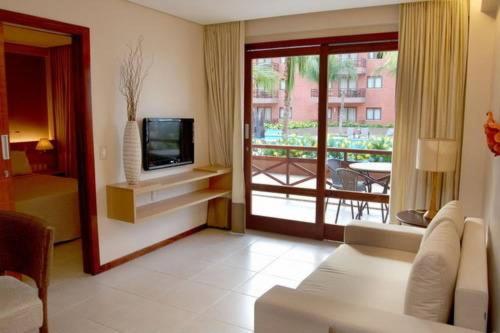 a living room with a television and a balcony at Residence Kariri Beach Cumbuco in Cumbuco