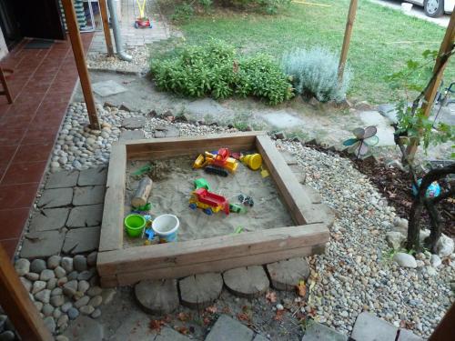 a sandbox with toys in the sand in a garden at Alföldi Vendégház in Hódmezővásárhely