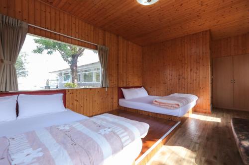 two beds in a room with a large window at Zhang Yi Ya Zhu Homestay in Baihe
