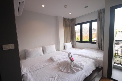 a bedroom with a white bed with a flower on it at Darin Hostel in Bangkok