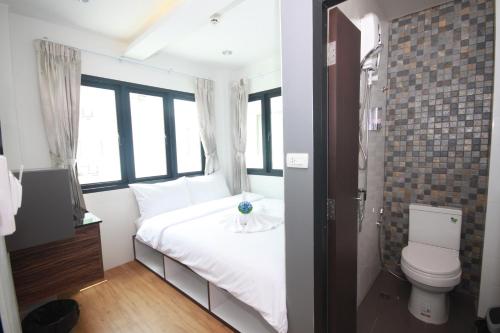 een slaapkamer met een wit bed en een toilet bij Darin Hostel in Bangkok