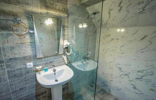 ein Bad mit einem Waschbecken und einer Glasdusche in der Unterkunft Hotel Tiflis in Achalziche