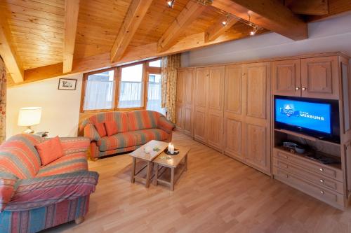 a living room with a couch and a tv at Appartements Zermatt Paradies in Zermatt