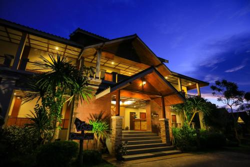 ein Haus mit einigen Palmen davor in der Unterkunft Phurua Resort in Phu Rua