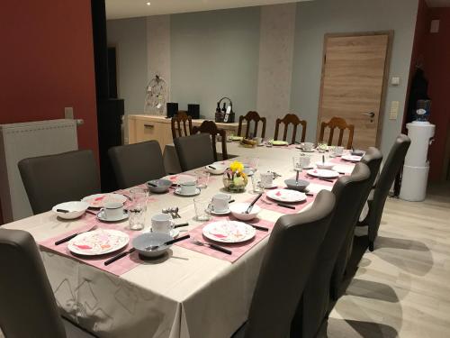 een lange tafel met stoelen en borden met eten erop bij La Colombe in Francorchamps