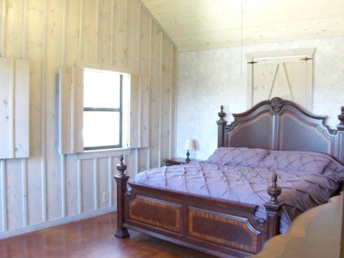 1 dormitorio con 1 cama en una habitación con paredes de madera en Breezy Hills Cottages - Moonlight Cottage en Fredericksburg