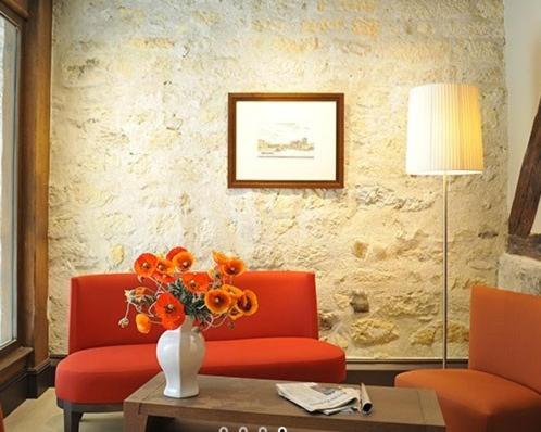 a living room with a couch and a vase with orange flowers at Hotel de L'Universite in Paris