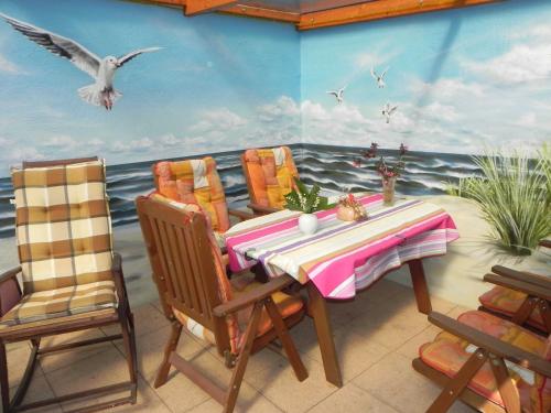 a table and chairs in a room with a painting of the ocean at Ferienunterkuenfte Schulz in Ahlbeck