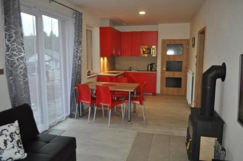 une cuisine avec des placards rouges, une table et des chaises dans l'établissement Moderni Domek Lipno, à Lipno nad Vltavou