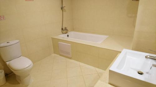 a bathroom with a tub and a toilet and a sink at Metropolis Hotel in Taoyuan