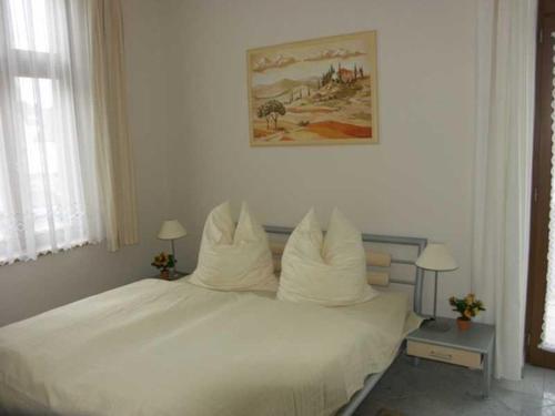 un letto bianco con cuscini bianchi sopra di Villa Bella Fw 4 Mit Meerblick 1 a Ahlbeck