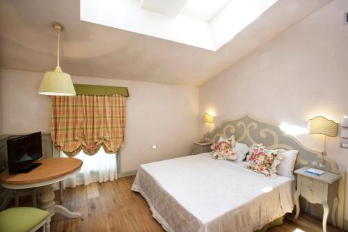 a bedroom with a bed and a table and a television at Casa del Vino della Vallagarina in Isera
