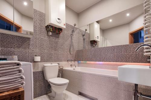 y baño con aseo, bañera y lavamanos. en PlayHouse Apartments, en Cracovia