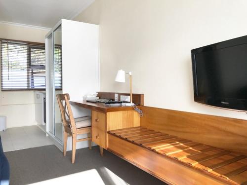 ウィンヤードにあるThe Waterfront Wynyardのデスク、壁掛けの大型テレビが備わる客室です。