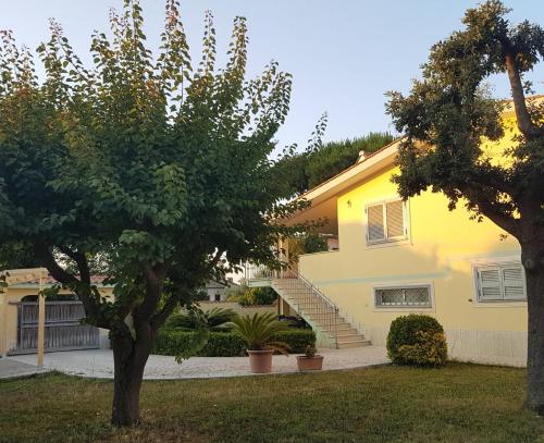 a yellow house with a tree in the yard at Clock's House in Fiumicino