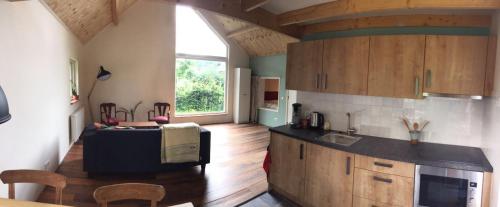 a kitchen with wooden floors and a large window at Huisje op Hamingen in Staphorst