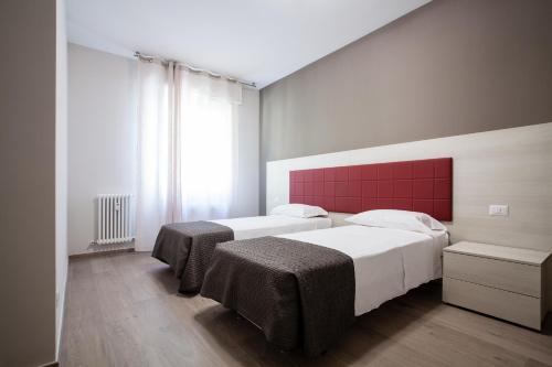 um quarto com 2 camas e uma cabeceira vermelha em Astoria Suite Apartments em Bolonha