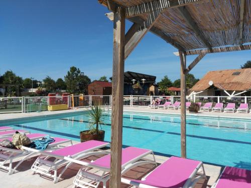 einen Pool mit rosa und weißen Stühlen und einem Pool in der Unterkunft MOBIL HOME 43 dans Camping 4 Etoiles in Gastes
