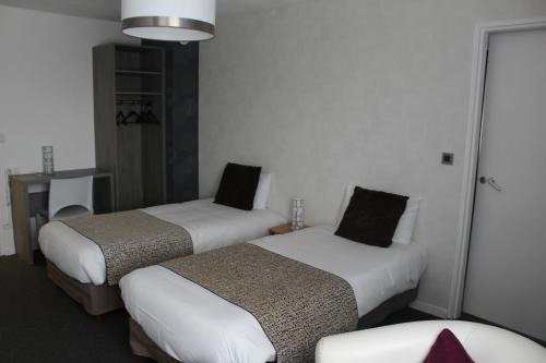 a hotel room with two beds and a chair at The Originals City, Hôtel La Terrasse, Tours Nord in Tours