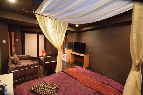 ein Schlafzimmer mit einem Himmelbett und einem Sofa in der Unterkunft Nuda by H-Seven (Adult Only) in Yokohama
