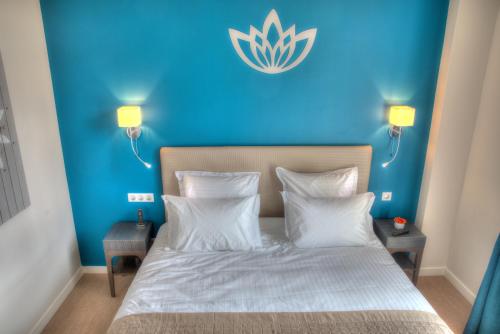 a blue bedroom with a bed with white sheets and pillows at Hôtel de la Tabletterie in Méru