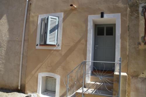 maison corse en balagne في Cateri: مبنى مع شرفة وباب ونافذة