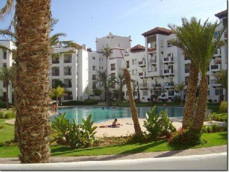 a large apartment building with a pool and palm trees at Appartement Luxe Marina Agadir in Agadir