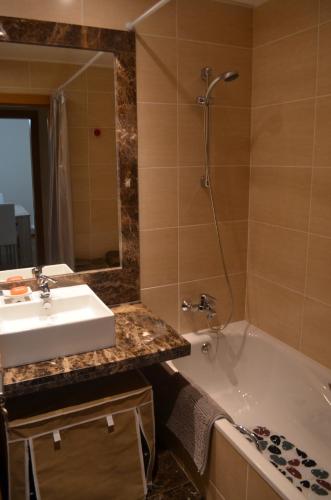 a bathroom with a sink and a tub and a mirror at Enzo Apartament in Funchal