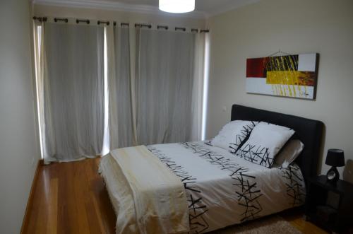 een slaapkamer met een bed met witte lakens en een raam bij Enzo Apartament in Funchal