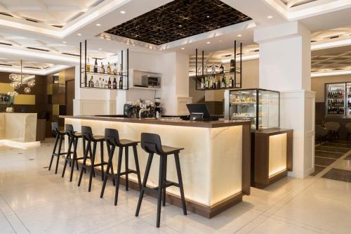 eine Bar in einem Restaurant mit schwarzen Stühlen in der Unterkunft Hotel Europa Splendid in Meran