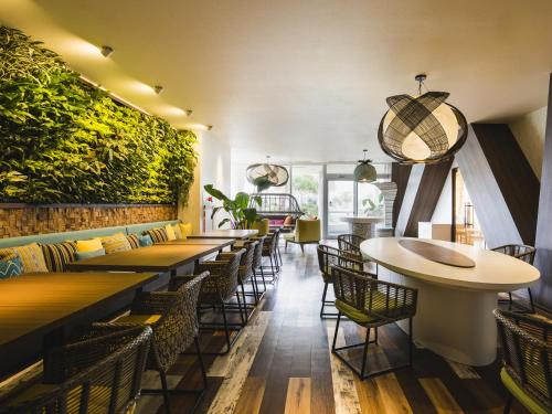 a restaurant with tables and chairs and plants on the wall at Sheraton Okinawa Sunmarina Resort in Onna