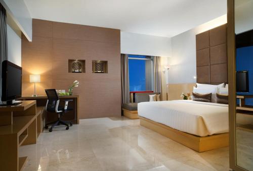 a hotel room with a bed and a desk and a television at Santika Premiere Dyandra Hotel & Convention - Medan in Medan