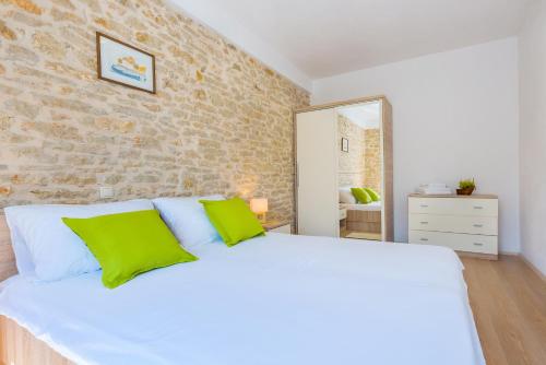 PuljaneにあるHoliday home Ana with pool national park krkaの緑の枕が付いた大きな白いベッドのある寝室