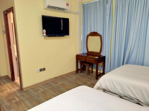 a room with two beds and a chair and a mirror at Uncle Ho Motel in Papar
