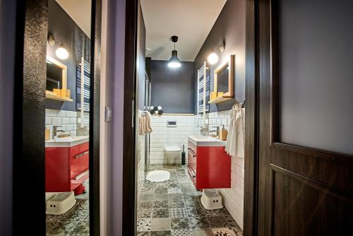 a bathroom with two sinks and a red cabinet at Apartamenty Kowary - Na Kowarskiej Starówce in Kowary