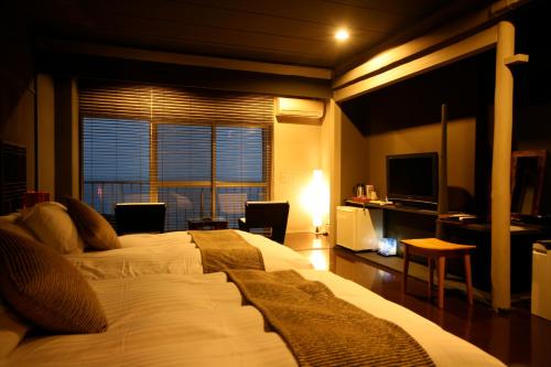 a bedroom with a large white bed and a window at Tabinoyado Ushionoakari Geiboso in Shima